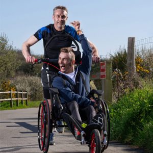 Le fauteuil roulant Hippocampe Marathon avec un utilisateur et un pousseur à pleine vitesse