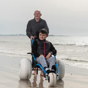 Fauteuil roulant Hippocampe plage et tout terrain avec un utilisateur sur le sable mouillé